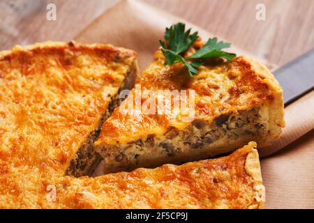 Torta tradizionale vegetale su tavola rustica di legno. Fetta di torta tagliata ripiena di funghi e formaggio. Primo piano. Foto Stock