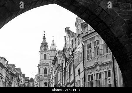 Distretto di Mala Strana a Praga, Repubblica Ceca. Una vista della vecchia strada con la Chiesa di San Nicola sullo sfondo da sotto la fine del Foto Stock