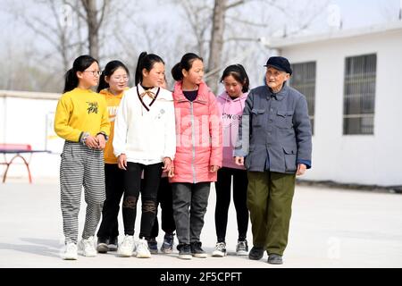 (210326) -- HEFEI, 26 marzo 2021 (Xinhua) -- Yan Mingyou parla con studenti che una volta hanno ricevuto il sostegno finanziario da Yan alla scuola primaria di Fuxing a Zhuwan Township della contea di Dingyuan, Chuzhou City, Provincia di Anhui della Cina orientale, 23 marzo 2021. Yan Mingyou, 92 anni, è ancora al posto dell'insegnamento della musica nelle scuole elementari rurali. Ritirandosi come insegnante rurale nel 1990, Yan si è offerto di insegnare musica agli studenti delle scuole rurali. Nel 1953, Yan lasciò l'esercito e tornò alla sua città natale, la Zhuwan Township, nella contea di Dingyuan. Ha rinunciato ad un lavoro migliore al governo locale e ha scelto w Foto Stock