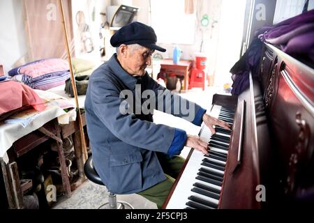 (210326) -- HEFEI, 26 marzo 2021 (Xinhua) -- Yan Mingyou suona il pianoforte presso il suo dormitorio a Zhuwan Township della contea di Dingyuan, Chuzhou City, nella provincia di Anhui, nella Cina orientale, 23 marzo 2021. Yan Mingyou, 92 anni, è ancora al posto dell'insegnamento della musica nelle scuole elementari rurali. Ritirandosi come insegnante rurale nel 1990, Yan si è offerto di insegnare musica agli studenti delle scuole rurali. Nel 1953, Yan lasciò l'esercito e tornò alla sua città natale, la Zhuwan Township, nella contea di Dingyuan. Ha rinunciato ad un lavoro migliore al governo locale e ha scelto di lavorare nelle scuole rurali, insegnando i vari soggetti come la politica Foto Stock