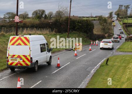 I lavoratori installano un cavo in fibra ottica sotto una strada rurale fuori Lisburn, Irlanda del Nord, Regno Unito Foto Stock