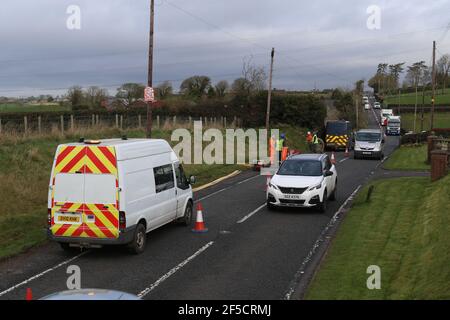 I lavoratori installano un cavo in fibra ottica sotto una strada rurale fuori Lisburn, Irlanda del Nord, Regno Unito Foto Stock