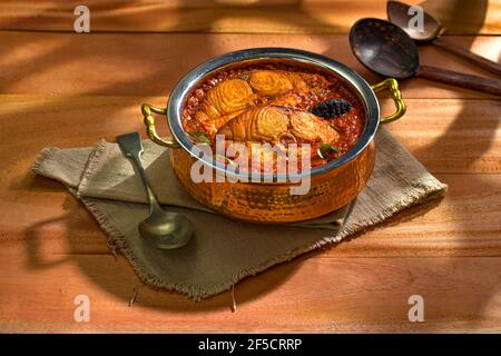 Pesce di cervo curry, curry tradizionale indiano di pesce, kerala speciale, disposto in una ciotola di servizio di rame guarnito con tamarindo malabarese e chil fresco verde Foto Stock