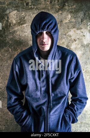 Ritratto di Young Man in una felpa con cappuccio presso la Vecchia parete Foto Stock