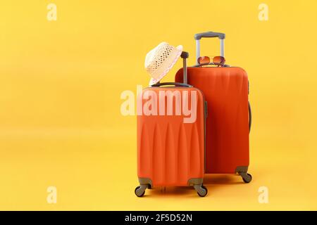 Due valigie di borse da viaggio, cappello di paglia e occhiali da sole su sfondo giallo con spazio per la copia. Concetto di tempo estivo, vacanza, turismo. Foto Stock