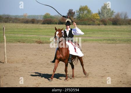 PUSZTA, UNGHERIA, SETTEMBRE 04. 2020: Pastori ungheresi come csikos in costume tradizionale folk che mostra i suoi cavalli addestrati nel puszta lowl ungherese Foto Stock