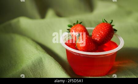 Gelatina di fragola rossa con bacche in un contenitore di plastica Foto Stock