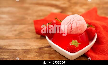 Gelatina di fragole in una ciotola, decorata con gelato fatto in casa Foto Stock