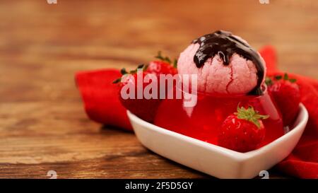 Gelatina di fragole in una ciotola, decorata con gelato fatto in casa Foto Stock