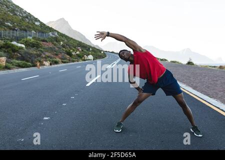 Uomo afroamericano che si esercita all'aperto su una strada costiera Foto Stock