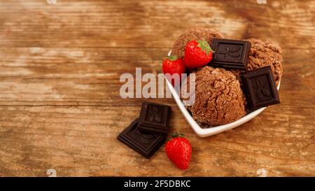 Gelato al cioccolato in una ciotola. Dessert decorato con cioccolato e fragole Foto Stock