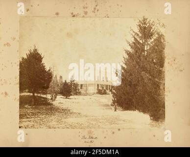 La Casa - Inverno. Vista in lontananza della casa di famiglia Seton a Cragdon. La neve copre il prato che circonda la casa, e molti grandi alberi sempreverdi crescono sul prato. Un uomo, forse Thomas E. Jevons, si trova di fronte alla telecamera di fronte a uno degli alberi sul lato destro dell'immagine. (Recto, mount) parte centrale inferiore, scritta a mano in inchiostro nero: 'The House / Winter' Foto Stock