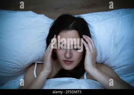 Donna stressata con mal di testa dormendo a letto con Insomnia Foto Stock