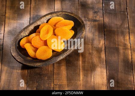 Albicocche secche biologiche nella ciotola di legno - Prunus armeniaca Foto Stock