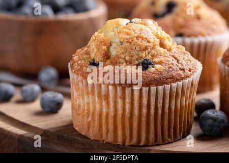 Primo piano di un muffin al mirtillo con frutti di bosco freschi su un piatto di legno Foto Stock