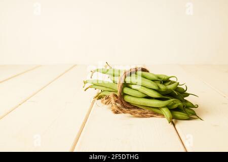 mazzo di fagioli verdi comuni crudi legati con un cordoncino su tavolo di legno bianco Foto Stock