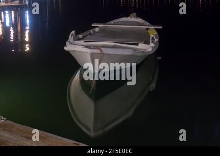 Lefkas in Grecia: Baia di Vliho di notte, con una piccola barca da pesca riflessa nelle acque ferme. Foto Stock