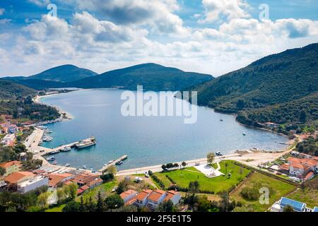 Drone aereo vista dall'alto delle fiabe colline valle con un lago blu rotondo, case di campagna con tegole rosse, giardini verdi estivi, nuvole bianche, sunn Foto Stock