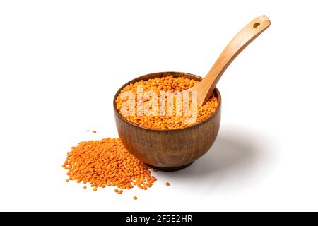 Semi crudi di lenticchie arancioni in ciotola di legno, cucchiaio isolato su sfondo bianco Vista dall'alto piatto piatto alimentazione sana, proteine vegetali concetto tradizionale Foto Stock