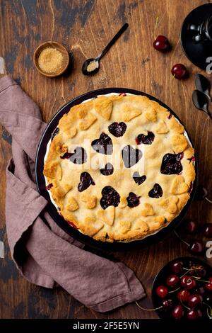 Torta di ciliegia gustosa fatta in casa con cuori su sfondo di legno. San Valentino prodotti da forno. Vista dall'alto Foto Stock