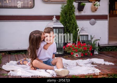 La sorella chiude gli occhi del fratello, in piedi dietro, giocando a peek-a-boo, ridendo. La bambina bacia il ragazzo sulla guancia, abbracci al camion del rimorchio, m Foto Stock