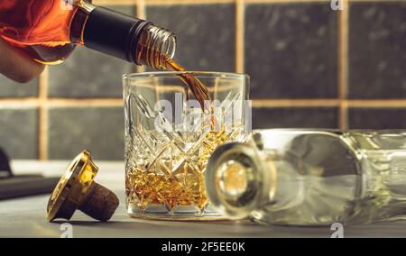 il whiskey viene versato in un bicchiere della bottiglia Foto Stock