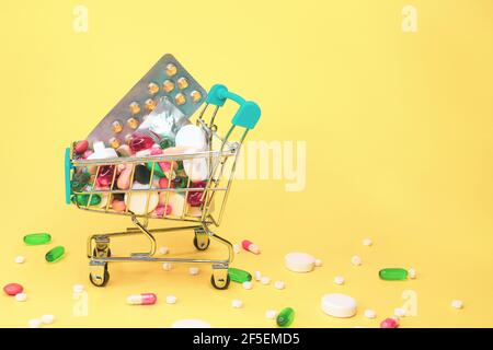mix di pillole colorate nel carrello su sfondo giallo. Molte compresse simbolo di trattamento complesso, abbondanza di farmaci farmacologici per aiutare con il dolore e. Foto Stock