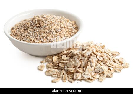 Farinata d'avena grossolana non cotta in una ciotola di ceramica bianca accanto a un mucchio di avena di porridge non cotta isolata su bianco. Foto Stock