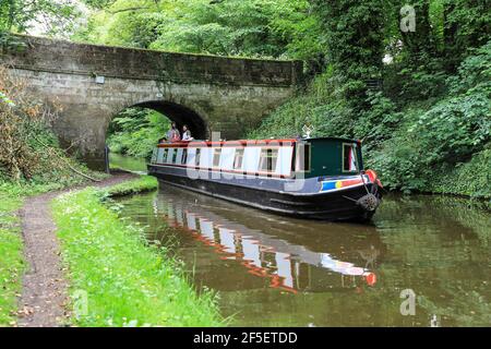 Una chiatta o una barca stretta che passa sotto il ponte numero 32 sul canale Shropshire Union, Gnosall, Staffordshire, Inghilterra, Regno Unito Foto Stock