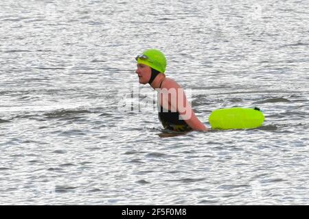 Lyme Regis, Dorset, Regno Unito. 26 Marzo 2021. Regno Unito Meteo. Un nuotatore emerge dal mare dopo aver fatto un tuffo in un pomeriggio fresco con occasionali incantesimi di sole a Lyme Regis in Dorset durante il blocco Covid-19. Picture Credit: Graham Hunt/Alamy Live News Foto Stock