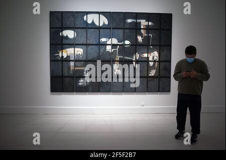 Un uomo che indossa una maschera facciale come precauzione contro la diffusione del covid-19 guardando il suo cellulare come si trova di fronte ad un dipinto esposto durante l'apertura della mostra al Centro d'Arte Contemporanea. Artista spagnolo Rafael Macarron, Mostra la sua prima mostra individuale 'Quince' in un museo spagnolo con quindici opere, di dipinti, disegni e sculture in bronzo di grande formato. Ha partecipato a mostre collettive e individuali in Spagna e in altri paesi. La mostra si terrà dal 26 marzo al 6 giugno 2021. Foto Stock