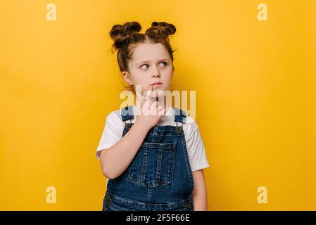 Pensieroso piccolo preschool ragazza bambino toccare il mento con il dito pensare o considerare, pensivo grazioso piccolo capretto che prende la decisione immaginare idea Foto Stock