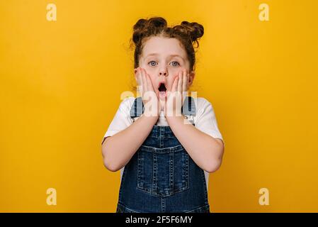 Sorpresa piccola ragazza preschool guardare fotocamera sentirsi stordito stupito da inattesa buona notizia, felice carino piccolo bambino scioccato da incredibile sorpresa Foto Stock