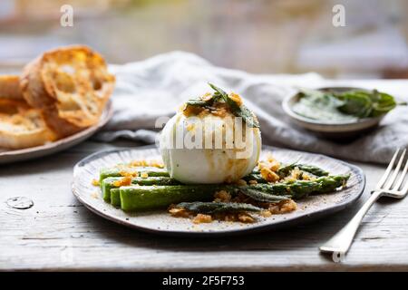 Mozzarella di bufala con aglio pungattato e salvia sugli asparagi Foto Stock