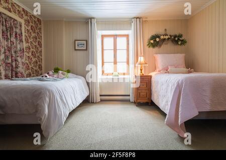 Due letti singoli e comodino in legno di pino nella camera da letto con moquette verde al piano superiore all'interno di un vecchio 1807 casa in stile cottage Foto Stock