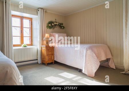 Due letti singoli e comodino in legno di pino nella camera da letto con moquette verde al piano superiore all'interno di un vecchio 1807 casa in stile cottage Foto Stock