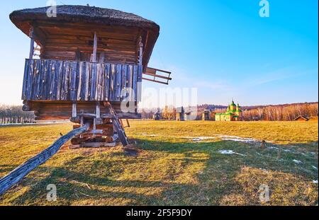 L'ampio prato verde da dietro il vecchio mulino a vento in legno, Pyrohiv Skansen, Kiev, Ucraina Foto Stock