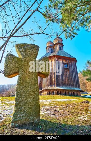 Legno medievale conservato Chiesa di San Michele e la pietra intagliata Cossack pietra tomba in primo piano, Pyrohiv Skansen, Kiev, Ucraina Foto Stock