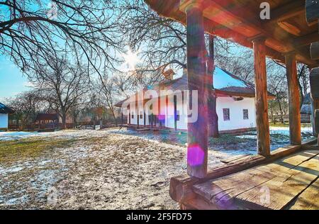 La corte umida paludosa della storica fattoria con una vista sul portico in legno e casa di hata imbiancata, Pyrohiv Skansen, Kyiv, Ucraina Foto Stock