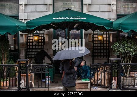 Pedoni che si coprono dalla pioggia tenendo ombrelloni nelle strade deserte del West End di Londra durante le misure di blocco del coronavirus, Inghilterra. Foto Stock