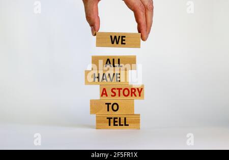Abbiamo tutti una storia da raccontare Symbol. Blocchi di legno con parole 'abbiamo tutti una storia da raccontare'. Mano uomo d'affari. Splendido sfondo bianco. Business, po Foto Stock