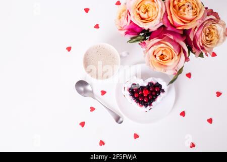 Torta da dessert romantica per San Valentino con rose. Biscotti dolci con crema e cuore rosso per un arredo bianco. Primo piano, spazio per la copia. Foto Stock