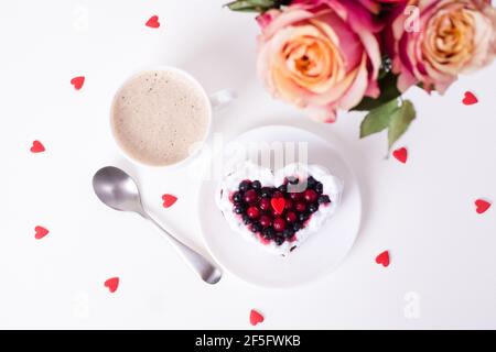 Torta da dessert romantica per San Valentino con rose. Biscotti dolci con crema e cuore rosso per un arredo bianco. Primo piano, spazio per la copia. Foto Stock