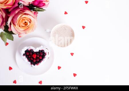 Torta da dessert romantica per San Valentino con rose. Biscotti dolci con crema e cuore rosso per un arredo bianco. Primo piano, spazio per la copia. Foto Stock
