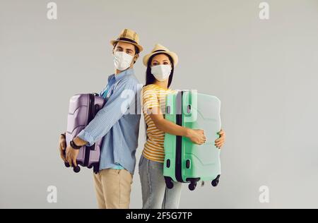 Felice famiglia coppia viaggiatore in maschera viso con valigia studio verticale Foto Stock