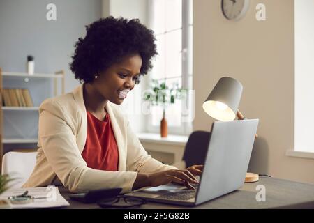 Giovane donna d'affari afro americana che lavora su un computer portatile con documenti elettronici. Foto Stock