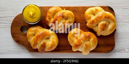 Pretzel morbidi di base fatti in casa con senape, vista dall'alto. Posa piatta, sovratesta, dall'alto. Foto Stock