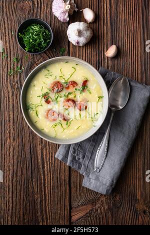 Zuppa di Caldo Verde fatta di cavolo savoia, patate puree, cipolla, aglio e fette di salsiccia fritte in una ciotola di ceramica su rustico fondo di legno Foto Stock
