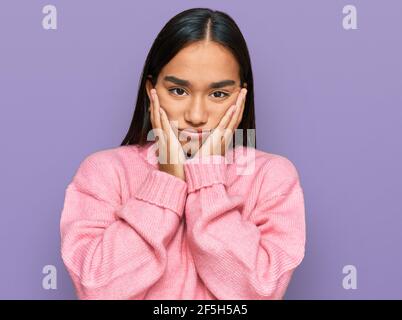 Giovane donna asiatica che indossa casual inverno maglione stanco mani che coprono viso, depressione e tristezza, sconvolto e irritato per il problema Foto Stock