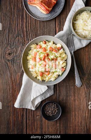 Kapustove halusky conosciuto come Strapacky, piatto classico in Slovacchia, gnocchi di patate bollite con crauti e cipolla, condito con pancetta fritta e fresco c Foto Stock